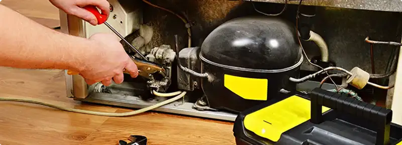 Refrigerator repair technician fixing the compressor and wiring in Saline, MI