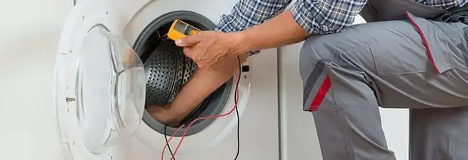 Dryer repair technician inspecting and repairing a clothes dryer in Ann Arbor, MI
