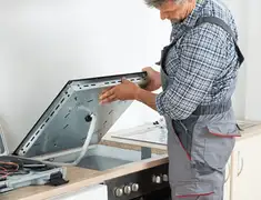 Appliance repair technician installing a built-in cooktop in Ann Arbor, MI