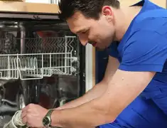 Dishwasher repair technician inspecting and servicing an open dishwasher in Ann Arbor, MI