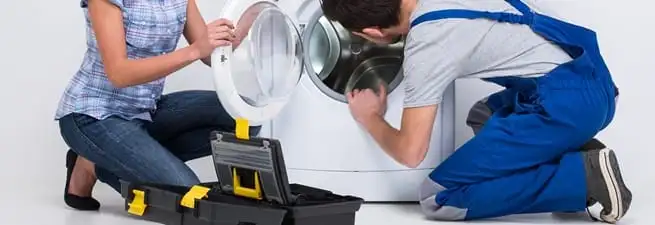 Washer repair technician inspecting a front-load washing machine with tools in Ann Arbor, MI
