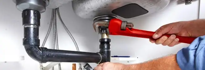 Garbage disposal repair technician tightening the sink drain and disposal connection in Ann Arbor, MI