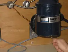 Garbage disposal repair technician tightening the mounting ring under a sink in Ann Arbor, MI