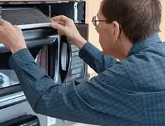 Appliance repair technician replacing a microwave vent filter in Ann Arbor, MI