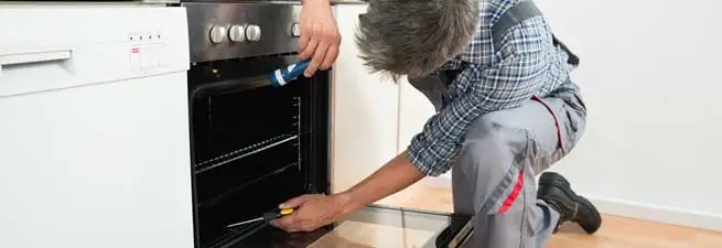 Oven repair technician inspecting and servicing an electric oven in Ann Arbor, MI