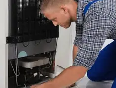 Refrigerator repair technician servicing the compressor and condenser area in Ann Arbor, MI