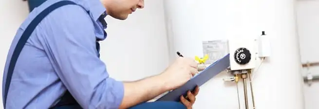 Water heater repair technician inspecting the unit and recording service notes in Ann Arbor, MI